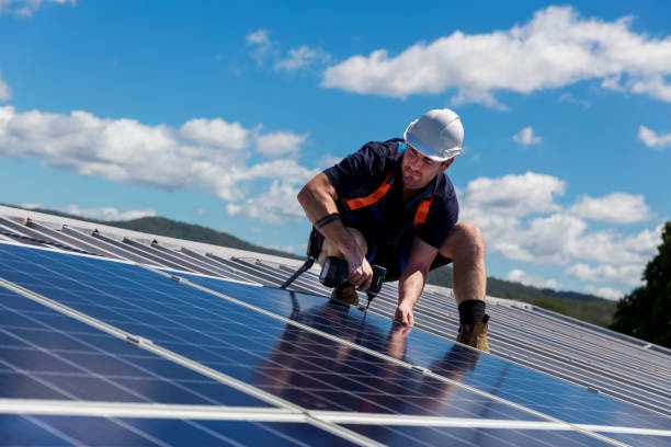 Solar panel installer with drill installing solar panels on roof on a sunny day Solar panel installer with drill installing solar panels on roof on a sunny day